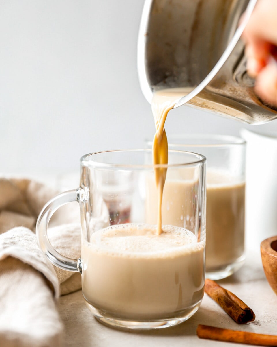 A person pouring liquid into a cup of coffee.