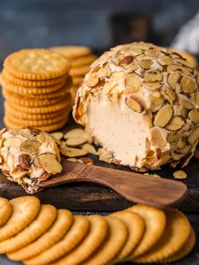 A delicious cheese ball recipe with almonds and crackers beautifully presented on a wooden board.