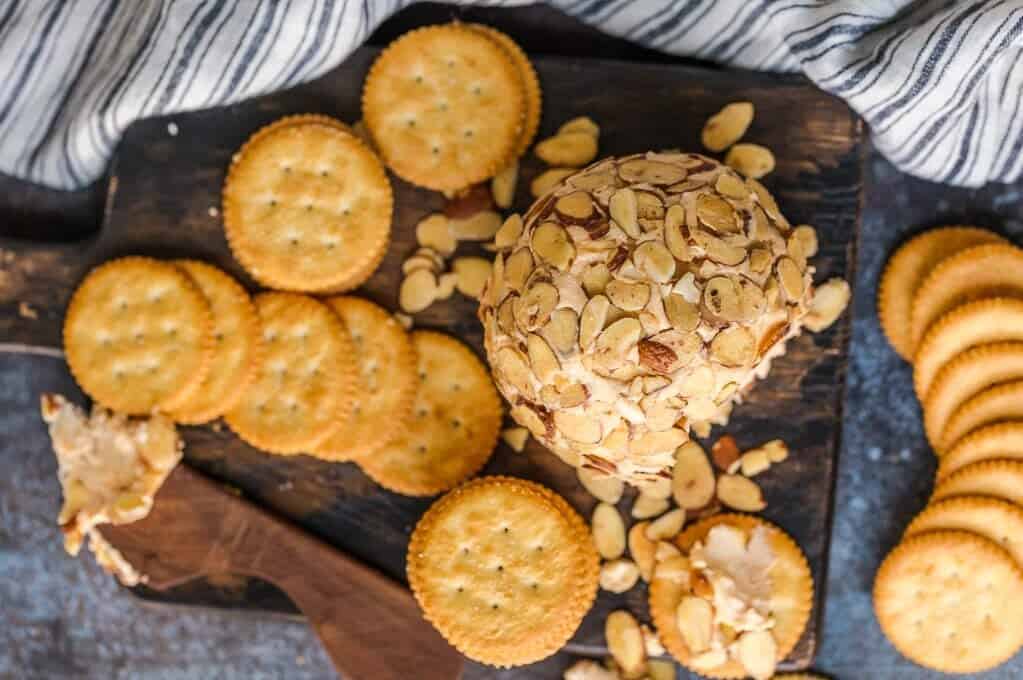 This is the BEST CHEESE BALL RECIPE for holiday parties. No Christmas or New Year's Eve party is complete without a classic cheese ball served with crackers! Wood board with a cheese ball and crackers