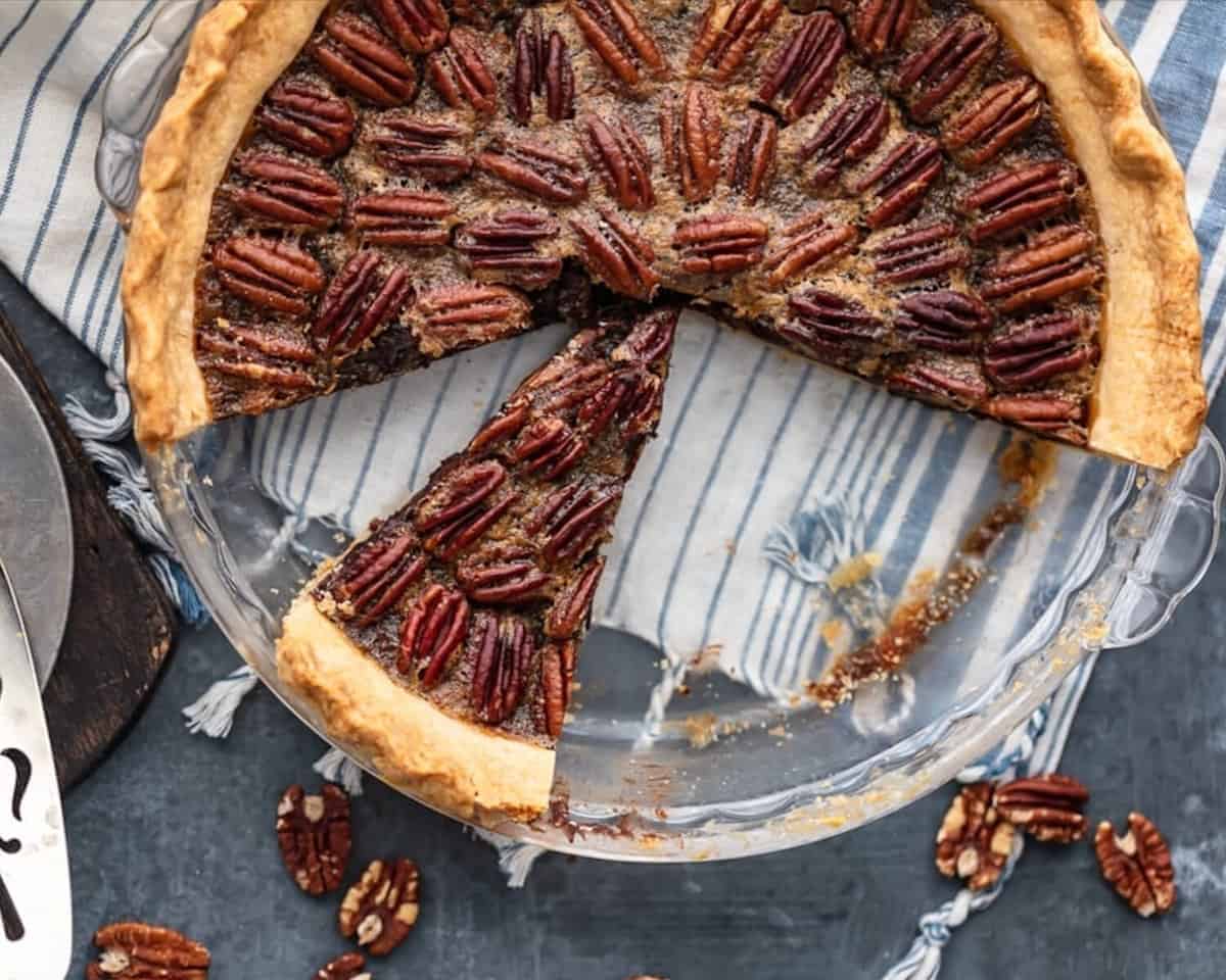 A chocolate pecan pie with a slice taken out of it.
