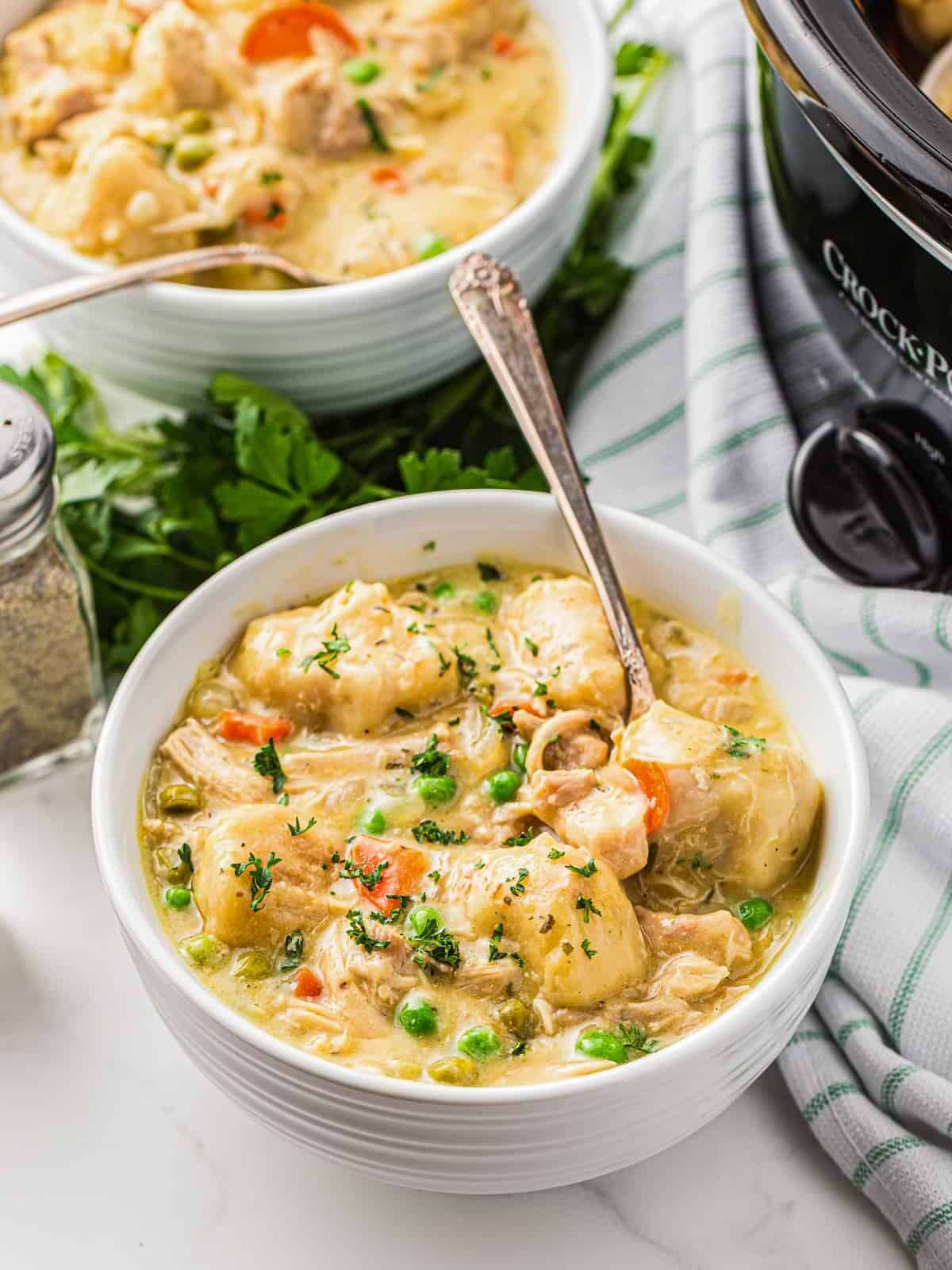 two bowls of chicken and dumplings with spoons.
