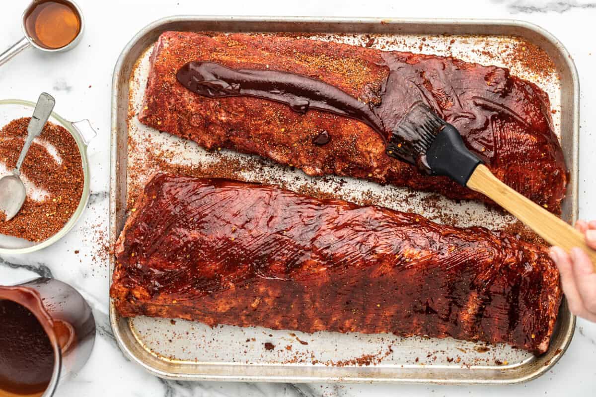 Slow cooker ribs on a baking sheet with a spatula.