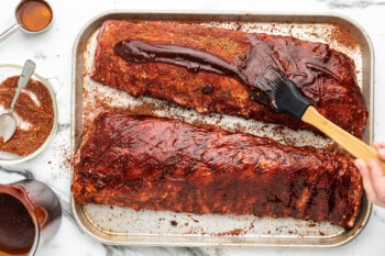 Slow cooker ribs on a baking sheet with a spatula.
