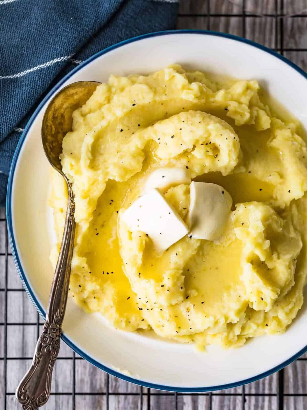 easy mashed potatoes in a bowl with butter and a serving spoon.