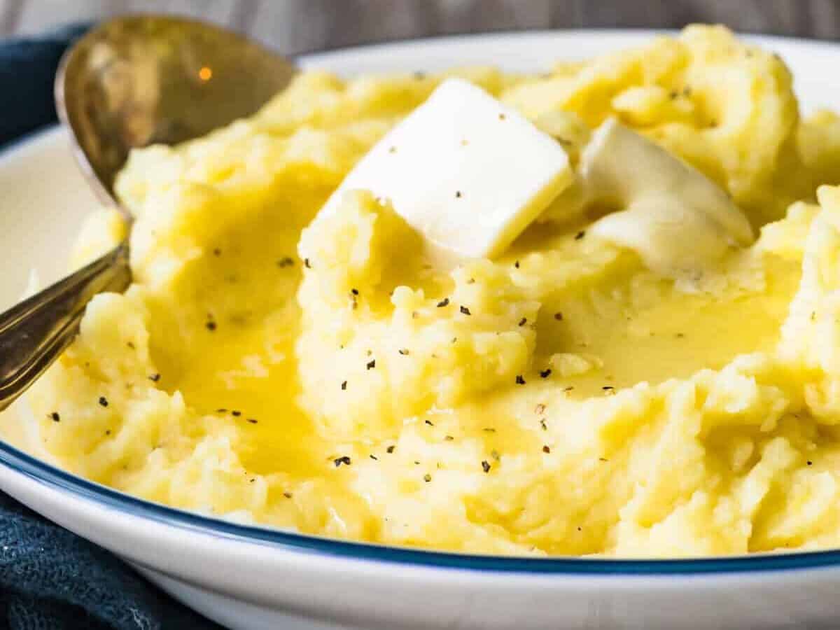 Fresh pepper on top of easy mashed potatoes in a bowl with a serving spoon.