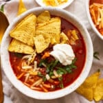 A bowl of beef tortilla soup with tortilla chips and sour cream.