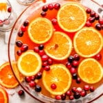 A bowl filled with oranges and cranberries.