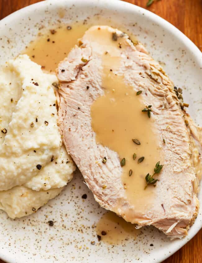 A plate of instant pot turkey breast with mashed potatoes and gravy on it.