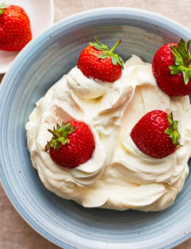 A blue plate with mascarpone cheese and strawberries.