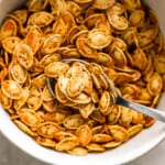 Pumpkin seeds in a bowl with a spoon.