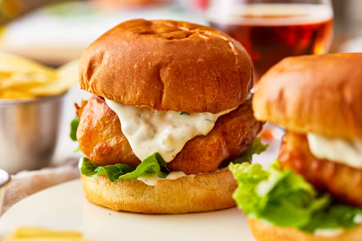 Two fried fish sandwiches with tartar sauce.
