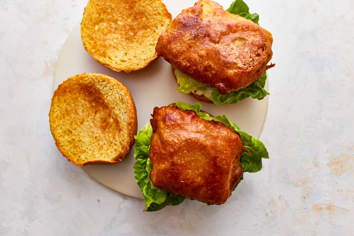 Two crispy fish sandwiches on a plate with lettuce.