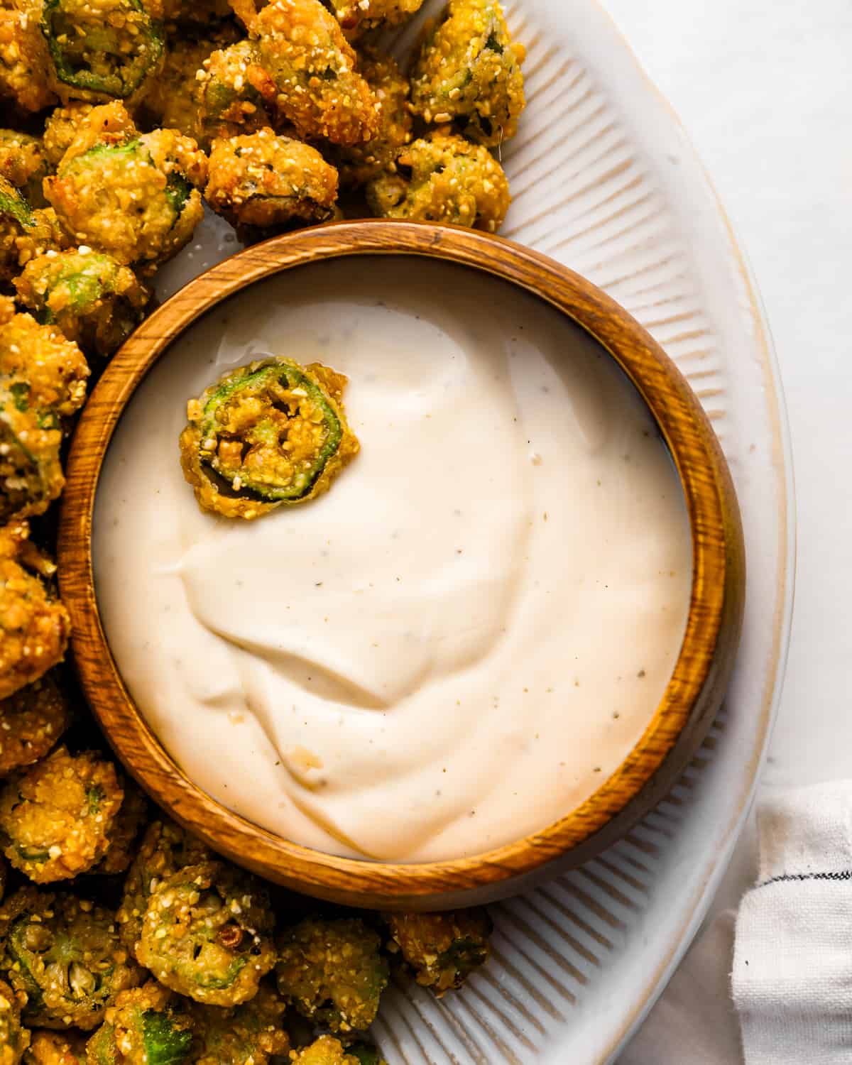 A bowl of fried okra with dipping sauce.
