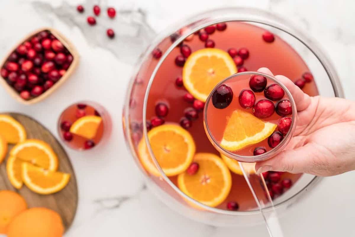 overhead image of hand holding a glass of holiday punch over a punch bowl