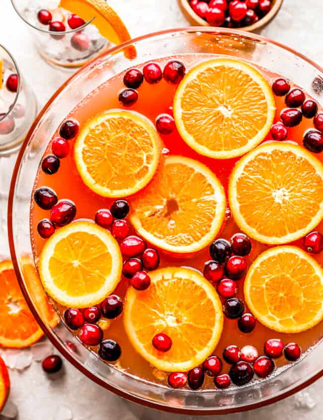 A bowl filled with oranges and cranberries.