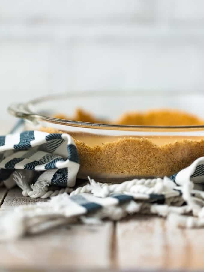 side view of graham cracker crust in a glass pie pan.