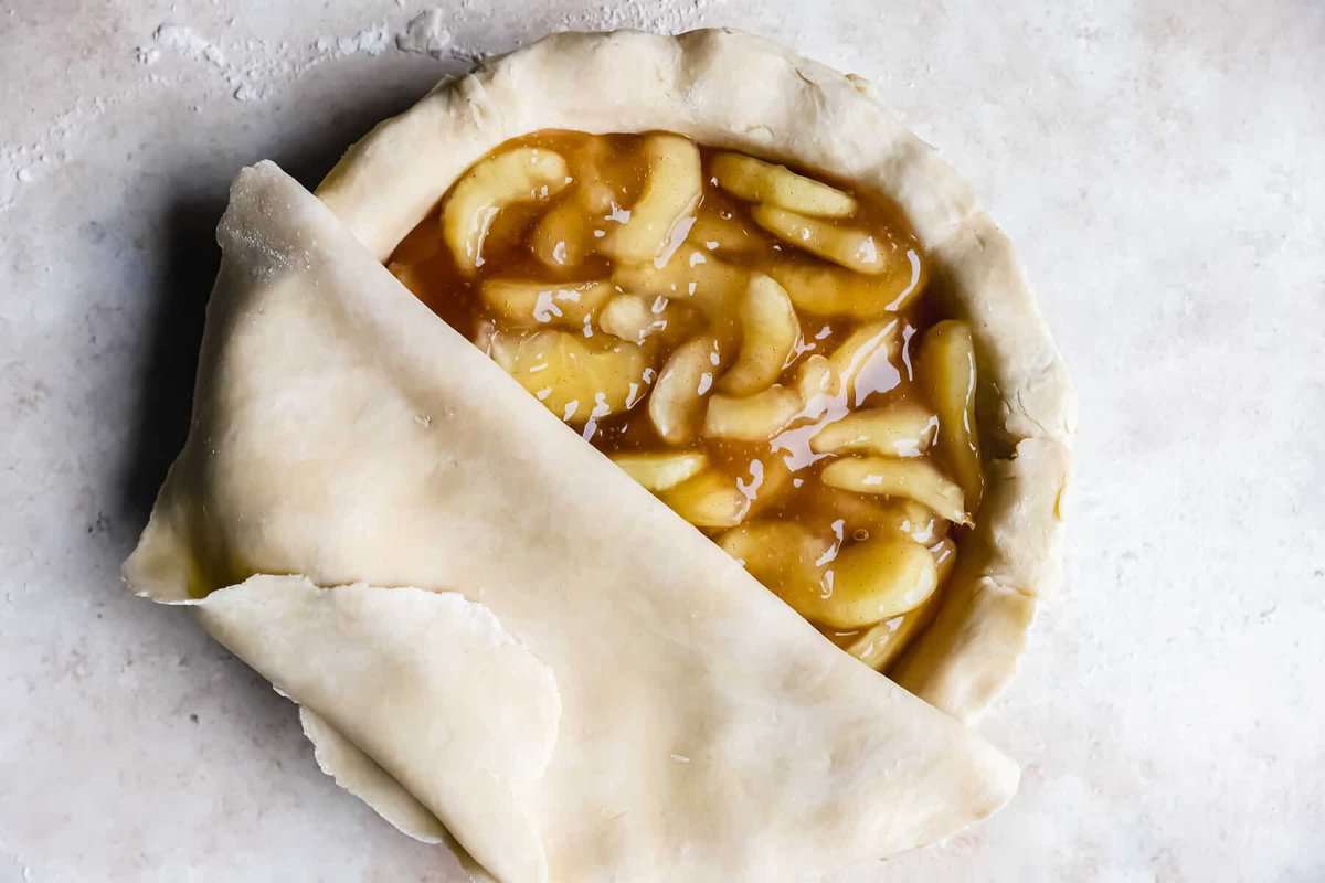 rolling pie crust on top of an apple pie