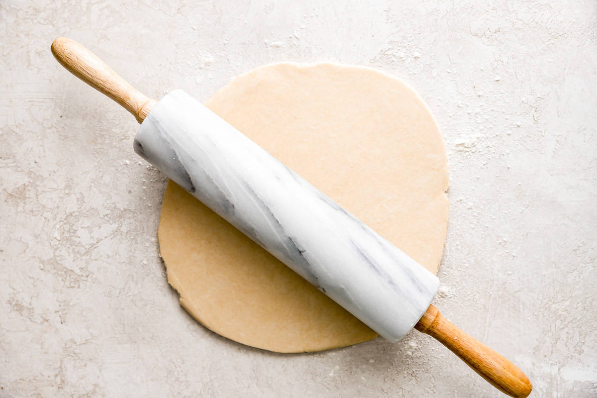 A rolling pin with a wooden handle on top of a piece of dough.