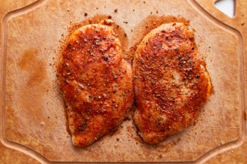 Two chicken breasts on a cutting board.