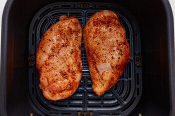 Two chicken breasts in an air fryer.