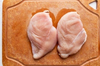 Two chicken breasts on a cutting board.