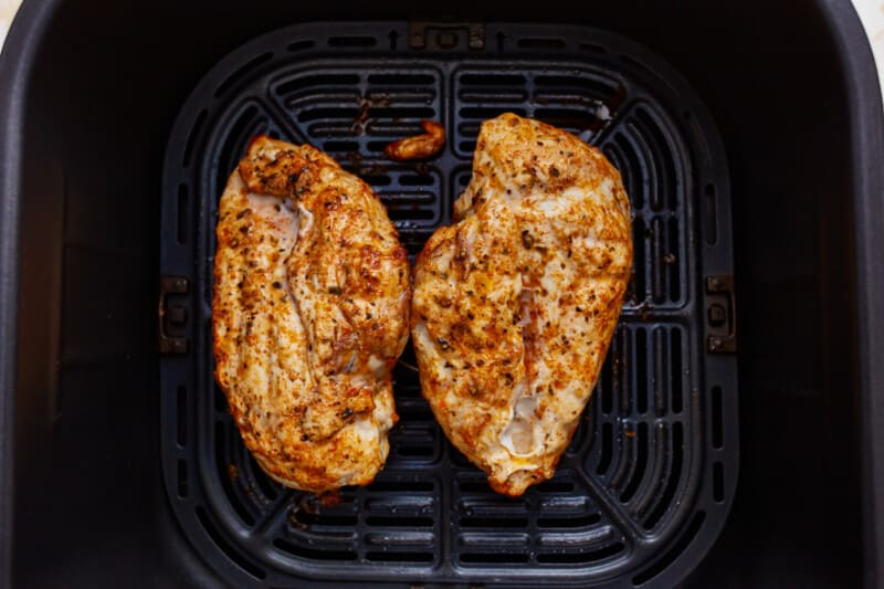 Two chicken breasts in an air fryer.