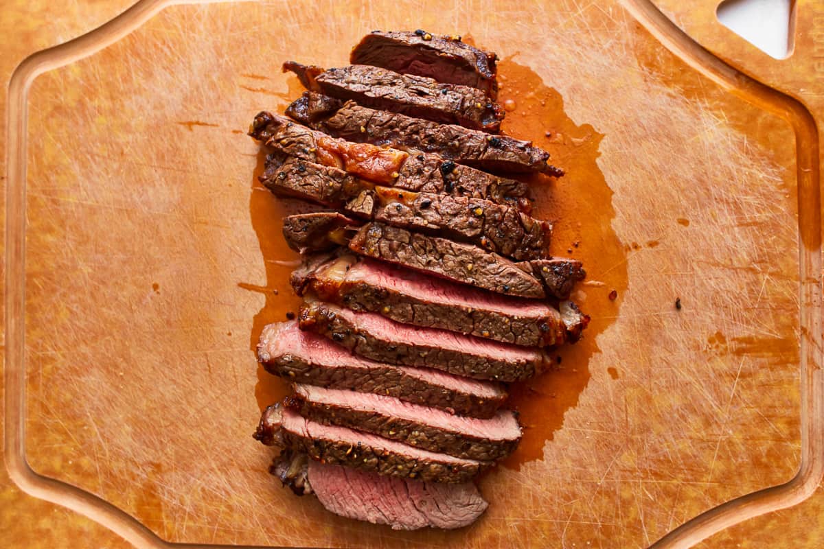 Sliced steak on a wooden cutting board.