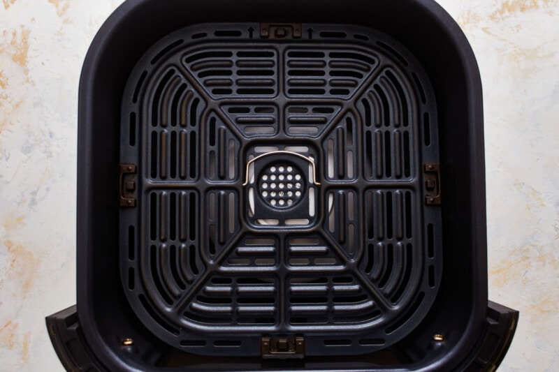 A close up of a black trash can on a white background.