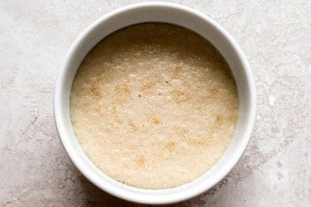 A bowl of brown sugar in a white bowl on a table.