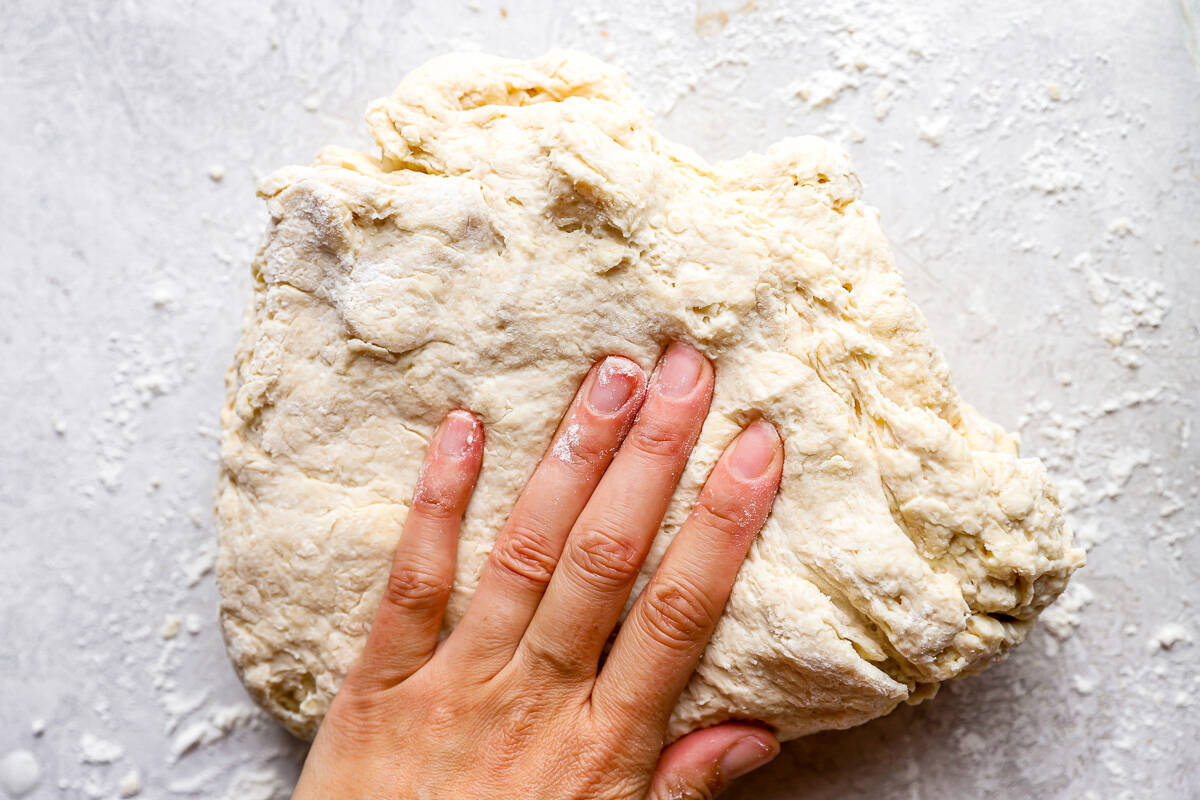 A person's hand is touching a piece of dough.