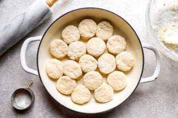 Biscuits in a pan next to a rolling pin.