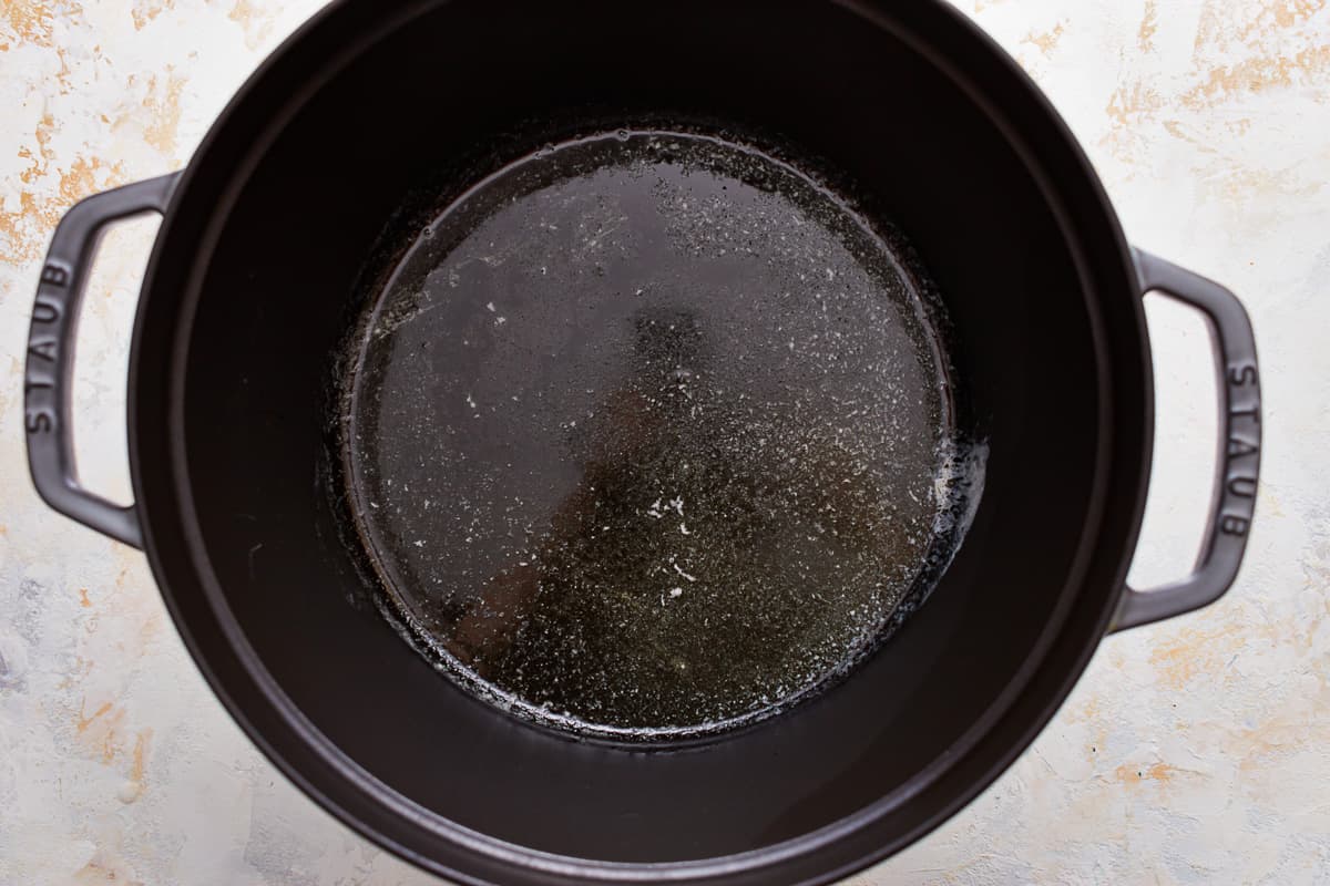 A black pot filled with oil on a table.