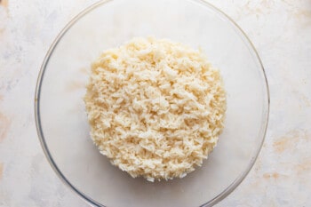 Rice in a glass bowl on a white surface.