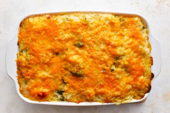 Cheesy broccoli casserole in a white dish.