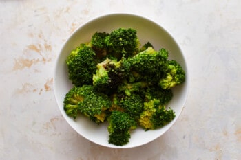 Broccoli in a white bowl on a table.