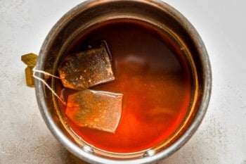 A cup of tea with tea bags in it.