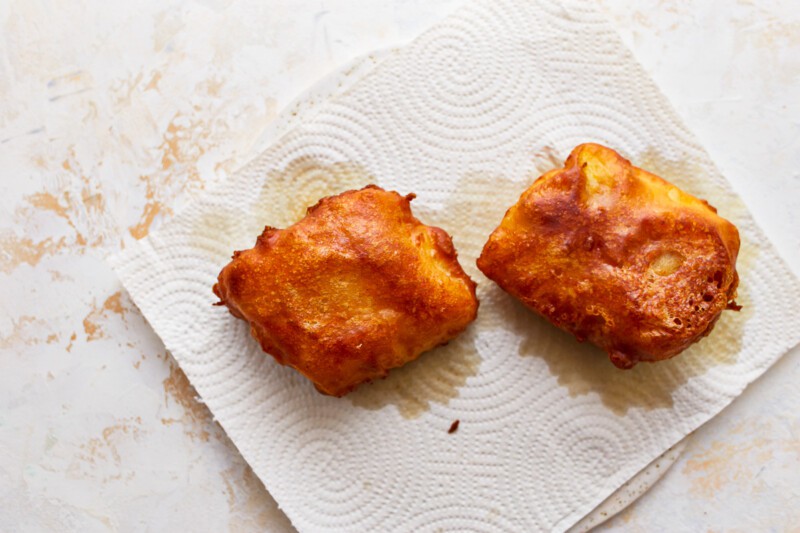 Two fried doughnuts on a napkin.