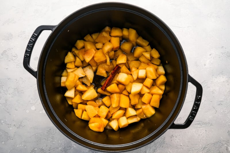 Sliced apples in a slow cooker on a gray surface.