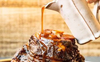 hand pouring glaze onto honey baked ham