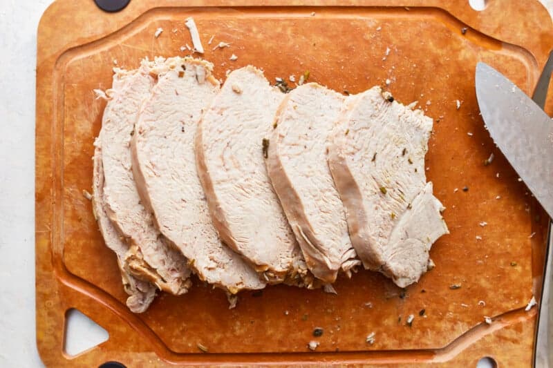 Sliced turkey on a cutting board with a knife.