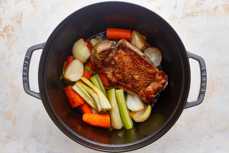 A black pot filled with carrots, celery and turkey.