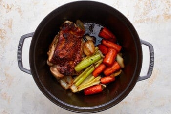 A pan with carrots, celery and turkey in it.