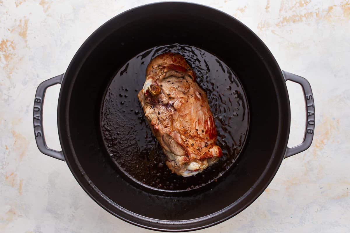 A piece of meat is being cooked in a pan.