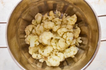Cauliflower in a metal pot on a white background.