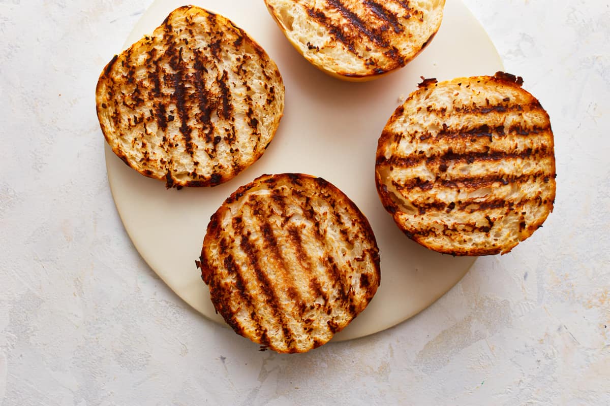 Toasted hamburger buns on a plate, with grill marks.