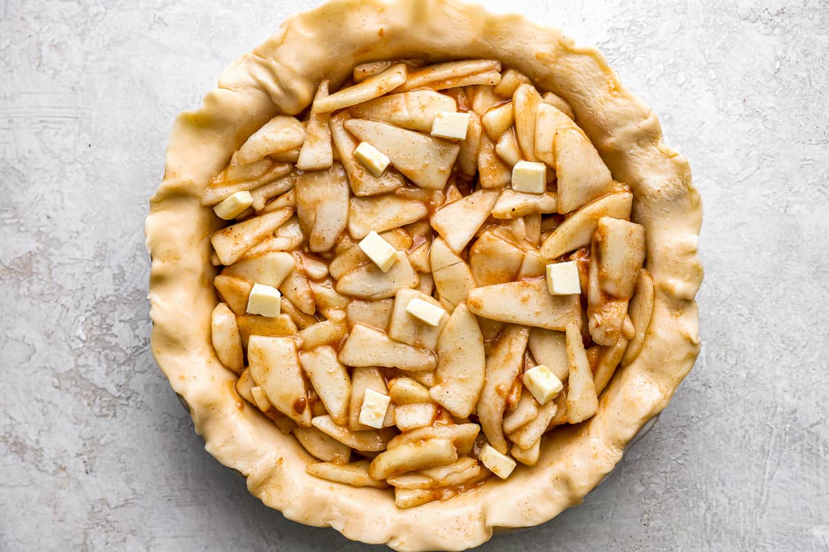 A pie crust filled with apples and butter.