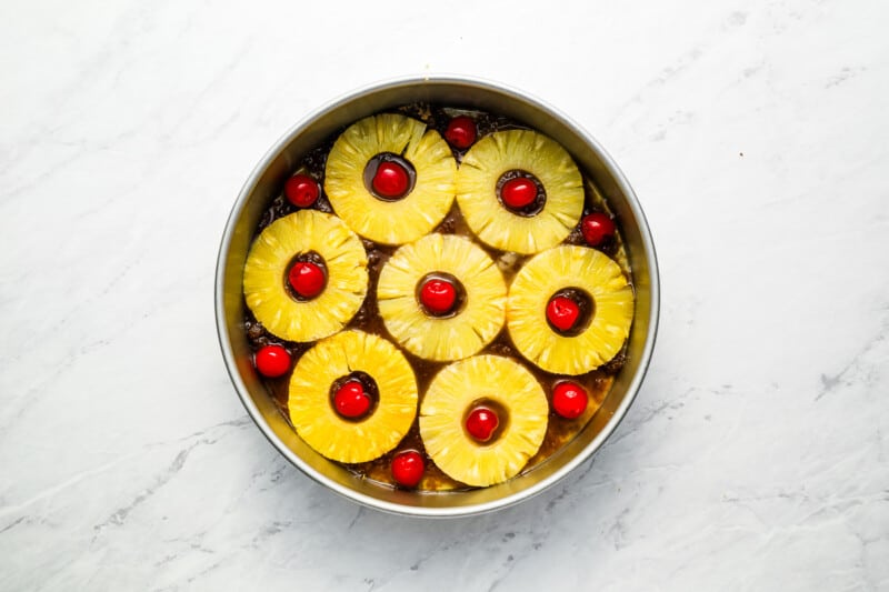 Pineapples in a pan with cherries on top.