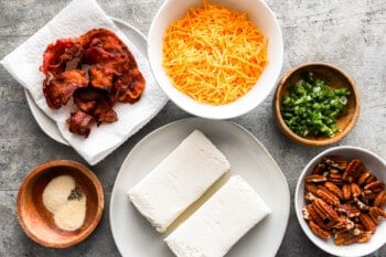 A bowl of bacon, cheese, and pecans on a table.