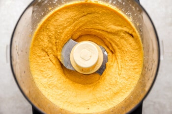 A food processor filled with a yellow mixture.