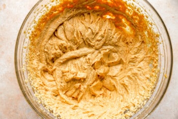 A bowl of peanut butter in a glass on a table.